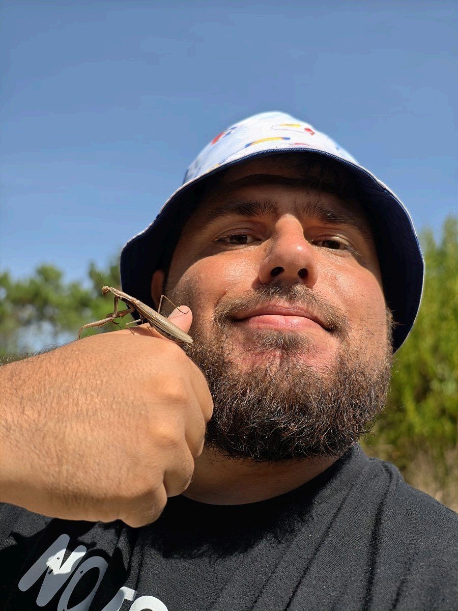 David en el campo, con un sombrero de pescador y una mantis posada en la mano